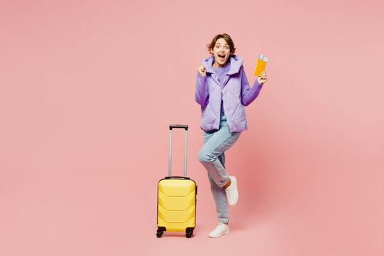 Traveler young woman wear vest casual clothes hold bag passport ticket isolated on plain pastel pink background. Tourist travel abroad in free spare time rest getaway. Air flight trip journey concept.
