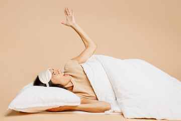 Outraged young sad mad Latin woman wears pyjamas jam sleep eye mask try to rest relax at home lay...