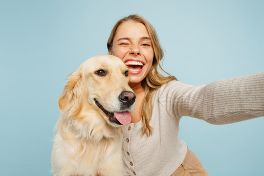 Close up young owner woman with her best friend retriever wears casual clothes do selfie shot on mobile cell phone hug dog isolated on plain pastel light blue background. Take care about pet concept.