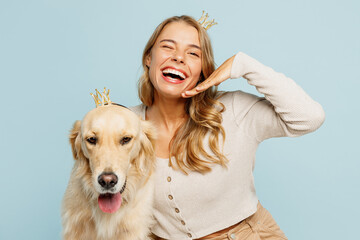 Young cheerful happy owner woman wearing casual clothes crown diadem hug cuddle best friend retriever dog hold face isolated on plain pastel light blue background studio. Take care about pet concept.