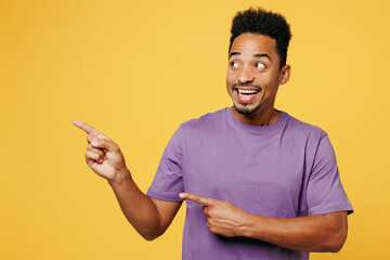 Young smiling man of African American ethnicity he wears purple t-shirt casual clothes point index...