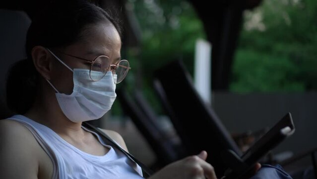 Asian woman wear glasses and mask using smartphone with unhappy expression
