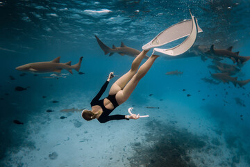 Slim woman snorkeling in a clear tropical water with nurse sharks in Maldives