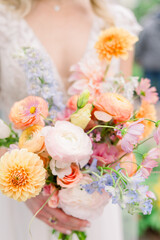 A close-up of a flower bouquet that a bride is holding on her wedding dress. 