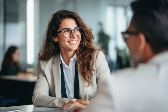 Smiling Young Business Woman Listening to Her Partner in Coworking Space