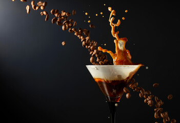 Espresso Martini drink with splashes and falling coffee beans on a black background.