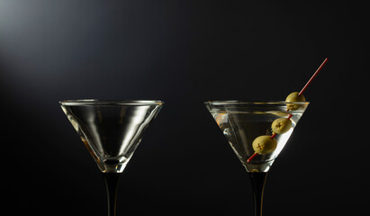 Glass of classic dry martini cocktail with lemon peel on a black background.