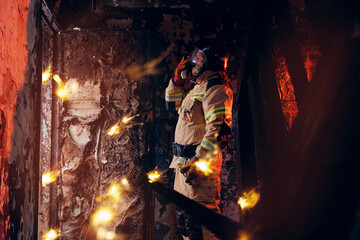 Portrait firefighter officer talking on radio walkie talkie with colleagues background wooden house...