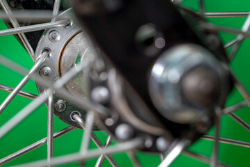 bicycle front wheel hub with spokes fitting detail on green background.