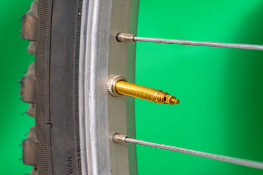 Presta valve without bicycle tire cap on green background.