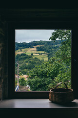 Front view of natural landscape as seen from the window of a house with a wicker basket on the...