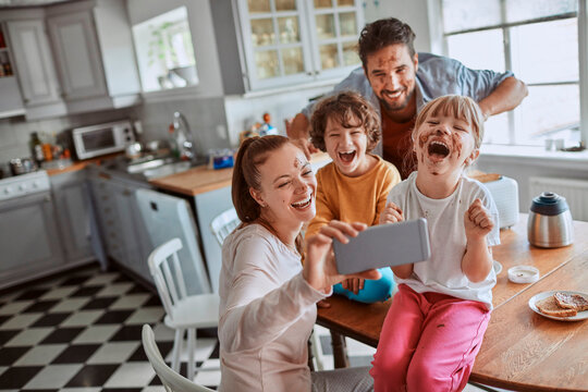 Happy family taking selfie with chocolate messy face in kitchen