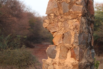 Closeup of a Broken and damaged stone pillar in selective focus in Trees bokeh Bhondsi, Pandala, closeup