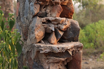 Closeup of a Broken and damaged stone wall and stone pillar in selective focus in Trees bokeh blur