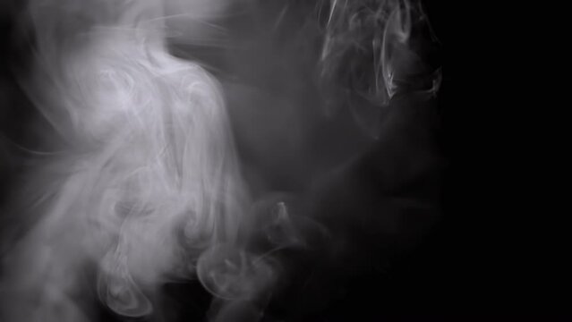 Whirlpool of Thick Clouds of Icy Smoke Fill Empty Space on a Black Background. Side. Abstract shapes. Texture. Beautiful curls of vapor swirl. Floating fog, flowing smoke. Blurred motion. Light. Fire.