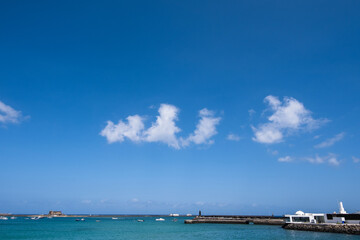 View of the Fermina islet. Turquoise blue water. Sky with big white clouds. Seascape. Lanzarote, Canary Islands, Spain.