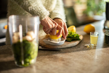 Woman is preparing a healthy detox smoothie in the kitchen - obrazy, fototapety, plakaty