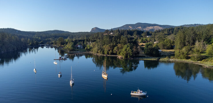 Boats at anchor in completely calm Deer Harbor on Orcas Island in the San Juans as golden hour approaches.