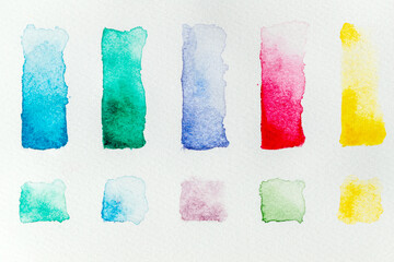 Watercolor paint swatches lined up in a grid on a white background, flat lay