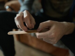 close-up of the hands of a young man sharpening his nails with a nail file made of natural materials