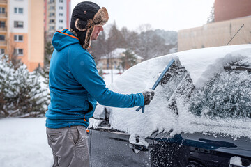 A man sweeps snow from his car.