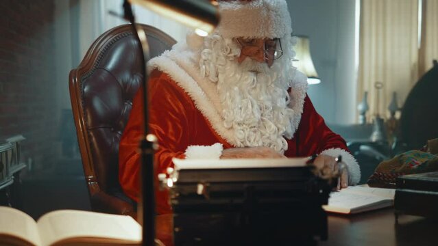 Santa Claus in his workshop, writing in his book a list of gifts on the work table
