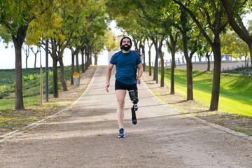 An amputee runner with a prosthetic leg jogs happily on a park's path, surrounded by trees and a peaceful ambiance.