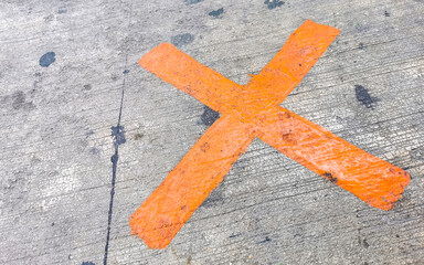 Orange painted cross on the sidewalk Playa del Carmen Mexico.