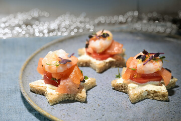 Canape sandwiches in star shape with shrimps and salmon on a blue plate, finger food snack for a...