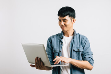 Portrait of confident Asian businessman, smiling and typing on a laptop keyboard, engaged in a successful online email or chat isolated on white background, showcasing his enthusiasm for technology.
