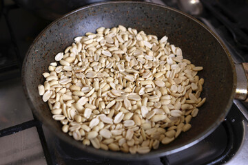 Raw peanuts are fried in a pan