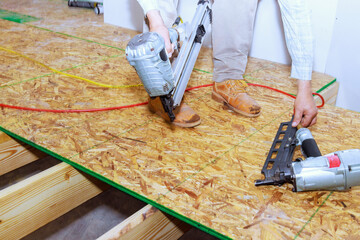 New home flooring is installed with wooden plywood using an air nail gun
