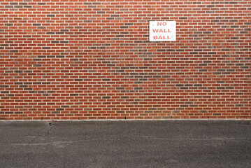 No wallball sign on a brick wall.  Little league baseball field.