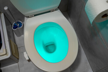 toilet illuminated with blue light inside by means of a device installed on its edge