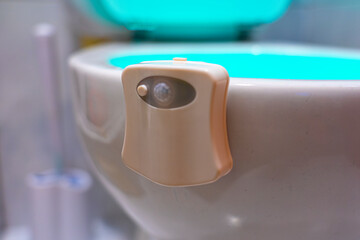 toilet illuminated with blue light inside by means of a device installed on its edge