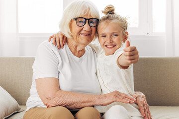 Woman grandmother love home granddaughter happy couch hugging girl sofa child family