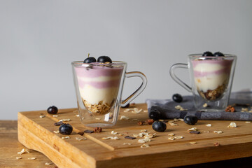 Müsli und Joghurt mit frischen Beeren auf rustikalem Tisch mit blauem Geschirrtuch und weißem...