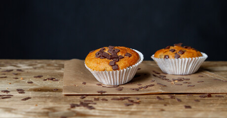 Frisch gebackene Schokoladenmuffins auf Geschirrtuch mit rustikalem Tisch und schwarzem Hintergrund