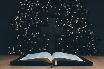 The open book of the Holy Bible. On the background is a Christmas tree. Prayer. Christmas and New...