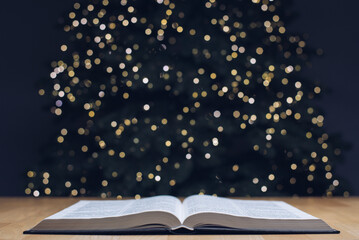 The open book of the Holy Bible. On the background is a Christmas tree. Christmas and New Year...