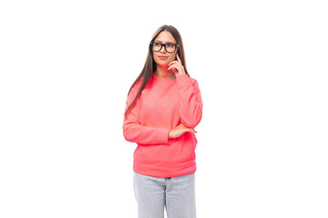 beautiful well-groomed young brunette european woman in glasses dressed in a pink sweatshirt on an isolated white background with copy space