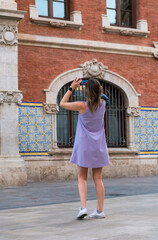 Fototapeta na wymiar Valencia, Spain -September 22th, 2023: Girl photographs the central market building in Valencia. From the woman's cell phone you can see the detail of the Mercad Central facade.