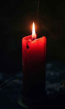 
One very short red candle near the bottom of the image burning in total darkness