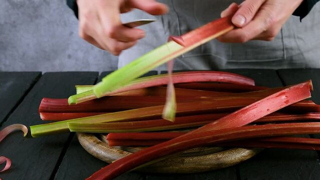 Women's hands clean rhubarb stems.