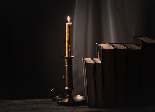 Candle illuminates old books