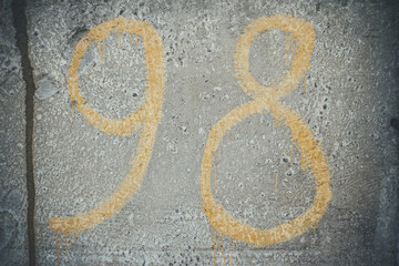 Yellow numbers on a concrete wall, number 98