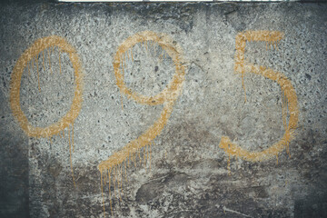 Yellow numbers on a concrete wall, number 0, 9, 5