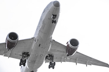 Fuselage seen from below of a large airplane with the landing gear deployed ready to land on a day with the sky covered in clouds
