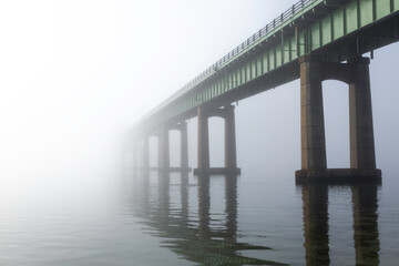 A bridge vanishes into fog and mist. Located at Captree State Park, Long Island New York. The...