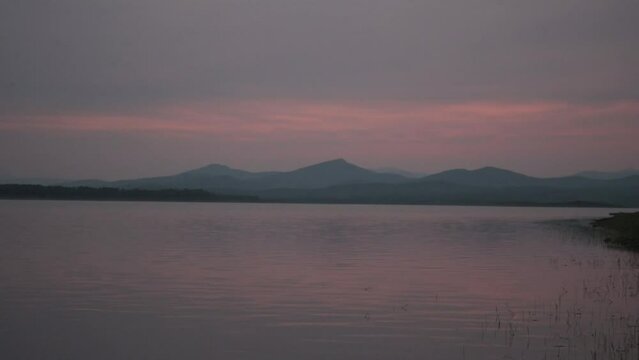 sunset in a swamp with mountains in the background at golden hour with turquoise tones horizontally